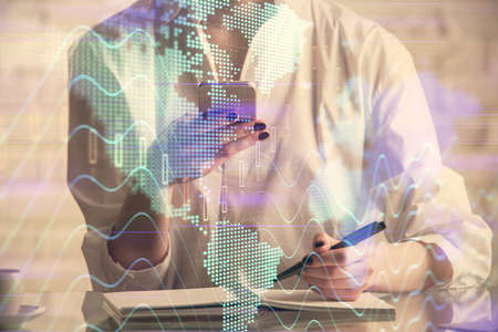 Double exposure of financial graph sketch hologram and woman holding and using a mobile device....