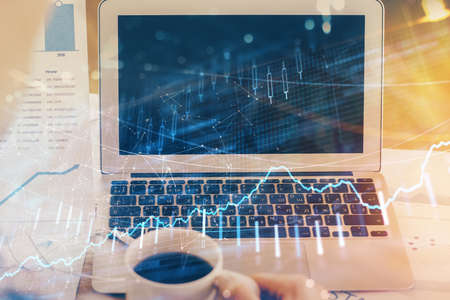Stock market graph on background with desk and personal computer. Double exposure. Concept of...