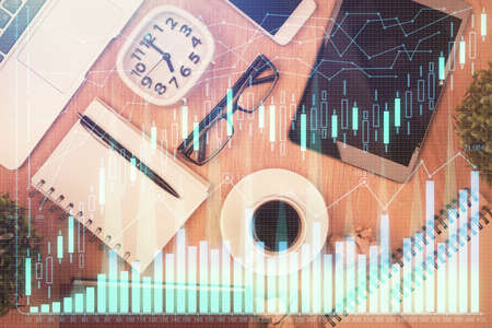 Double exposure of financial chart hologram over desktop with phone. Top view. Mobile trade platform...