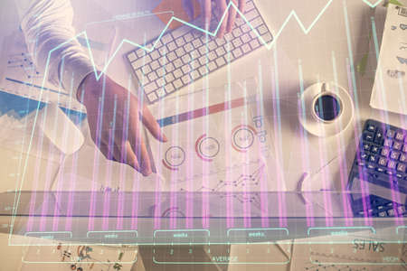 Multi exposure of mans hands typing over computer keyboard and forex graph hologram drawing. Top...