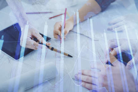 Double exposure of forex graph drawing and man and woman working together holding and using a mobile...