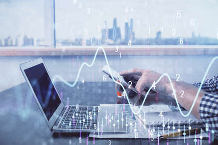 Double exposure of mans hands holding and using a digital device and forex graph drawing. Financial...