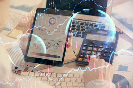Double exposure of mans hands holding and using a digital device and forex graph drawing. Financial...
