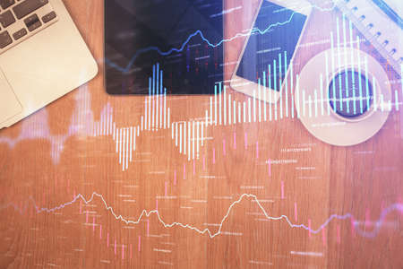 Double exposure of financial chart hologram over desktop with phone. Top view. Mobile trade platform concept.の写真素材