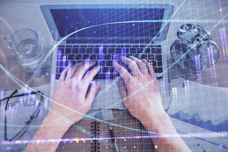 Multi exposure of mans hands typing over computer keyboard and forex graph hologram drawing. Top...