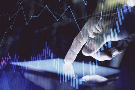 Double exposure of mans hands holding and using a digital device and forex graph drawing. Financial...