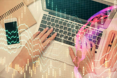 Double exposure of woman hands working on computer and forex graph hologram drawing. Top View....
