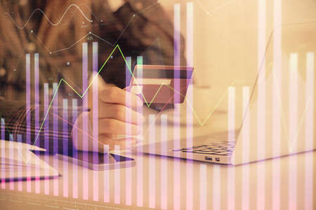 Multi exposure of woman on-line shopping holding a credit card and financial graph drawing. Stock...