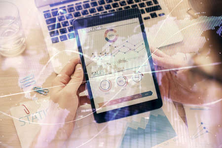 Double exposure of mans hands holding and using a digital device and forex graph drawing. Financial...