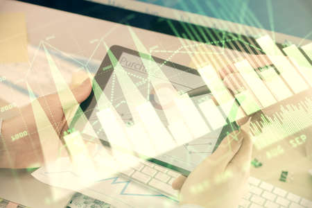 Double exposure of mans hands holding and using a phone and financial chart drawing. Market analysis...