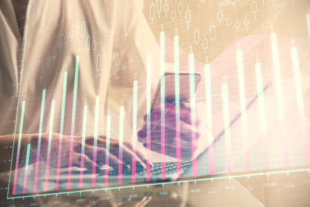 Double exposure of financial graph sketch hologram and woman holding and using a mobile device....