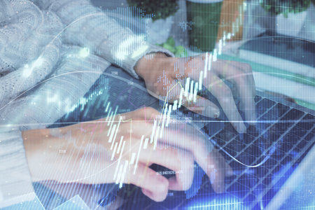 Double exposure of woman hands typing on computer and forex chart hologram drawing. Stock market...