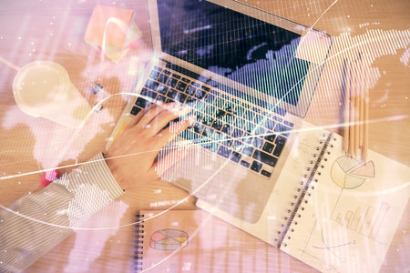 Double exposure of mans hands typing over computer keyboard and forex graph hologram drawing. Top view. Financial markets concept.の写真素材