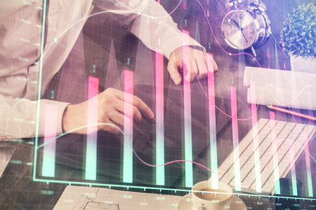 Double exposure of mans hands holding and using a phone and financial graph drawing. Analysis concept.の写真素材