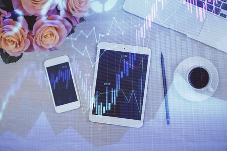 Double exposure of forex graph hologram over desktop with phone. Top view. Mobile trade platform concept.の写真素材