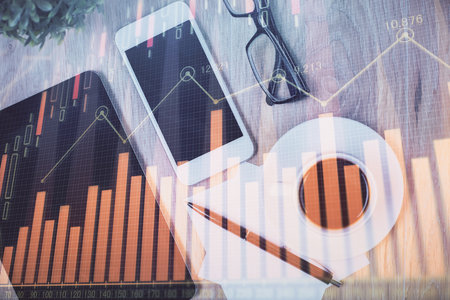 Double exposure of forex chart hologram over desktop with phone. Top view. Mobile trade platform concept.の写真素材