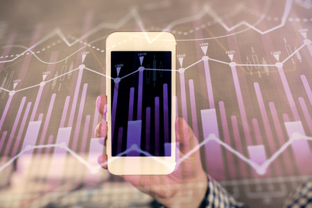Double exposure of mans hands holding and using a digital device and forex graph drawing. Financial market concept.の写真素材