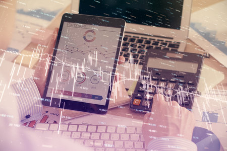 Double exposure of mans hands holding and using a digital device and forex graph drawing. Financial market concept.の写真素材