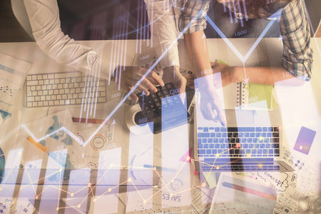 Double exposure of man and woman working together and financial graph hologram drawing. market analysis concept. Computer background. Top View.の写真素材