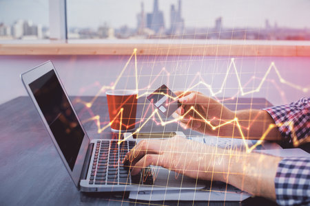 Double exposure of man hands holding a credit card and Forex graph drawing. Stock trading and...
