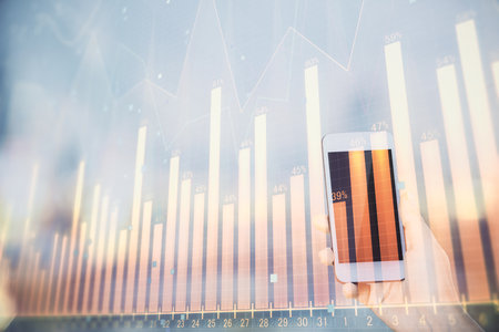 Double exposure of forex chart sketch hologram and woman holding and using a mobile device. Stock market concept.の写真素材
