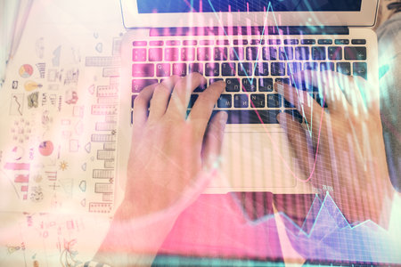 Double exposure of mans hands typing over laptop keyboard and forex chart hologram drawing. Top view. Financial markets concept.の写真素材