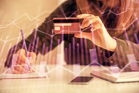 Double exposure of woman on-line shopping holding a credit card and financial graph drawing. Stock market E-commerce concept.の写真素材