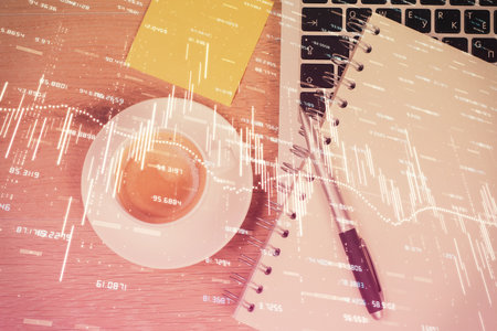 Double exposure of financial chart drawing over table background with computer. Concept of research and analysis. Top view.の写真素材