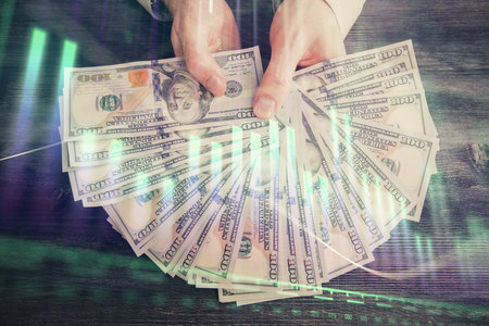 Multi exposure of financial graph drawing hologram and USA dollars bills and man hands. Analysis concept.の写真素材