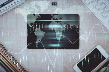 Double exposure of forex graph hologram over desktop with phone. Top view. Mobile trade platform...