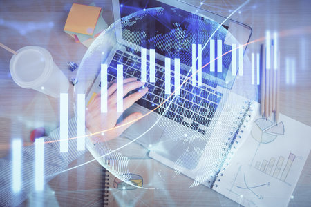 Double exposure of mans hands typing over computer keyboard and forex graph hologram drawing. Top view. Financial markets concept.の写真素材