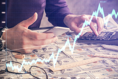 Double exposure of mans hands holding and using a digital device and forex graph drawing. Financial...