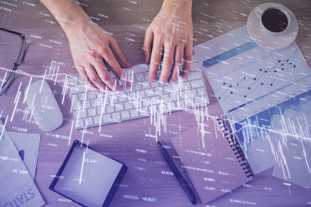 Multi exposure of mans hands typing over computer keyboard and forex graph hologram drawing. Top...