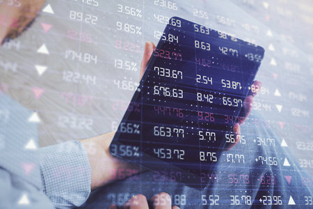 Double exposure of mans hands holding and using a digital device and forex graph drawing. Financial market concept.の写真素材