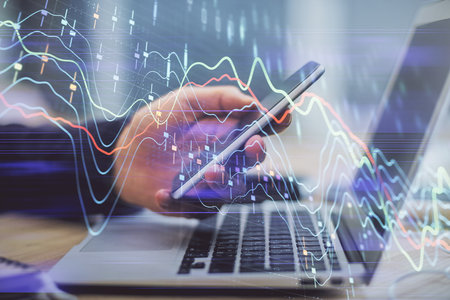 Double exposure of mans hands holding and using a phone and financial graph drawing. Analysis...