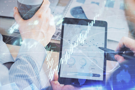 Double exposure of mans hands holding and using a phone and financial chart drawing. Market analysis...