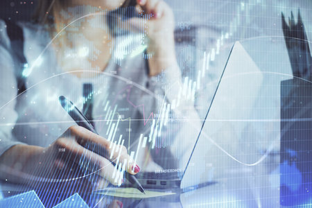 Double exposure of woman hands typing on computer and financial graph hologram drawing. Stock market...