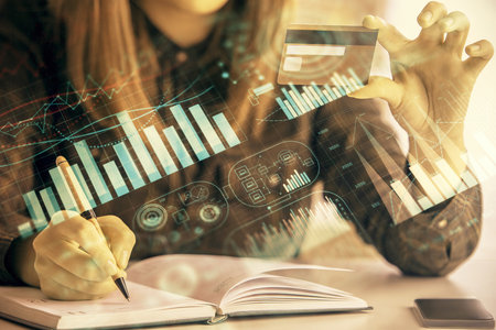 Multi exposure of woman on-line shopping holding a credit card and financial graph drawing. Stock market E-commerce concept.の写真素材