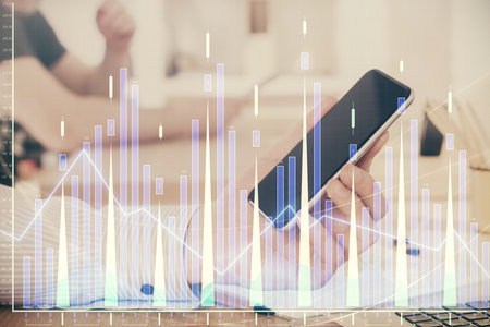 Double exposure of mans hands holding and using a digital device and forex graph drawing. Financial market concept.の写真素材