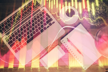Financial market graph and top view computer on the desktop background. Double exposure. Investment...