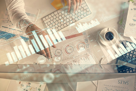 Multi exposure of mans hands typing over computer keyboard and forex graph hologram drawing. Top...