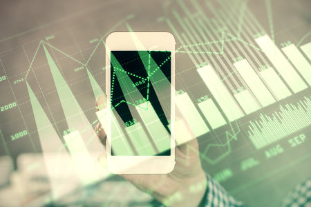 Double exposure of mans hands holding and using a digital device and forex graph drawing. Financial market concept.の写真素材