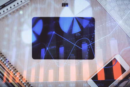Double exposure of forex graph hologram over desktop with phone. Top view. Mobile trade platform concept.の写真素材
