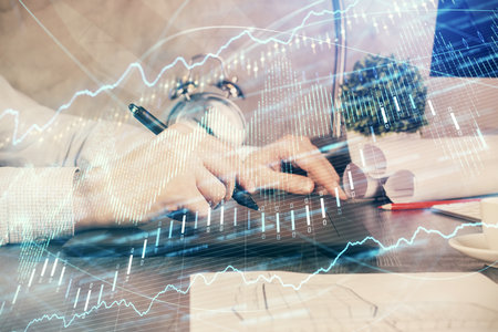 Double exposure of mans hands holding and using a phone and financial graph drawing. Analysis concept.の写真素材
