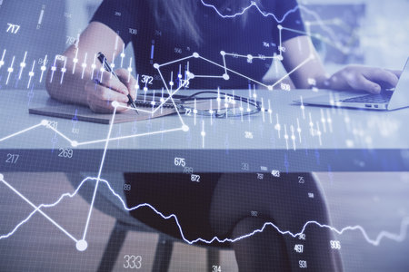 Double exposure of businesswoman hands typing on computer and forex chart hologram drawing....