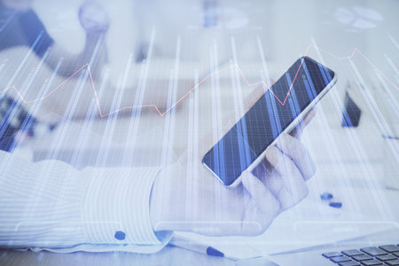 Double exposure of mans hands holding and using a digital device and forex graph drawing. Financial market concept.の写真素材