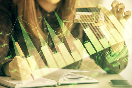 Multi exposure of woman on-line shopping holding a credit card and financial graph drawing. Stock market E-commerce concept.の写真素材
