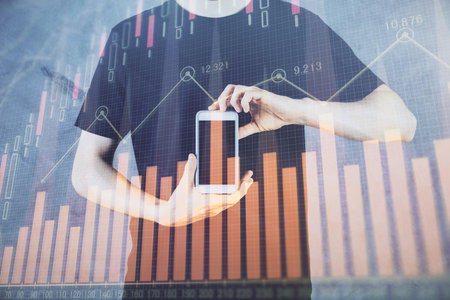 Double exposure of mans hands holding and using a digital device and forex graph drawing. Financial market concept.の写真素材