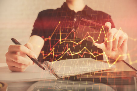 Double exposure of man hands holding a credit card and Forex graph drawing. Stock trading and digital fintech in Internet E-commerce concept.の写真素材