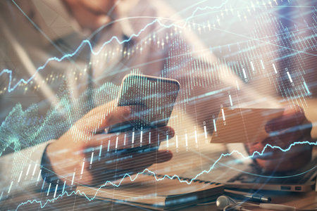 Double exposure of mans hands holding and using a phone and financial graph drawing. Analysis...